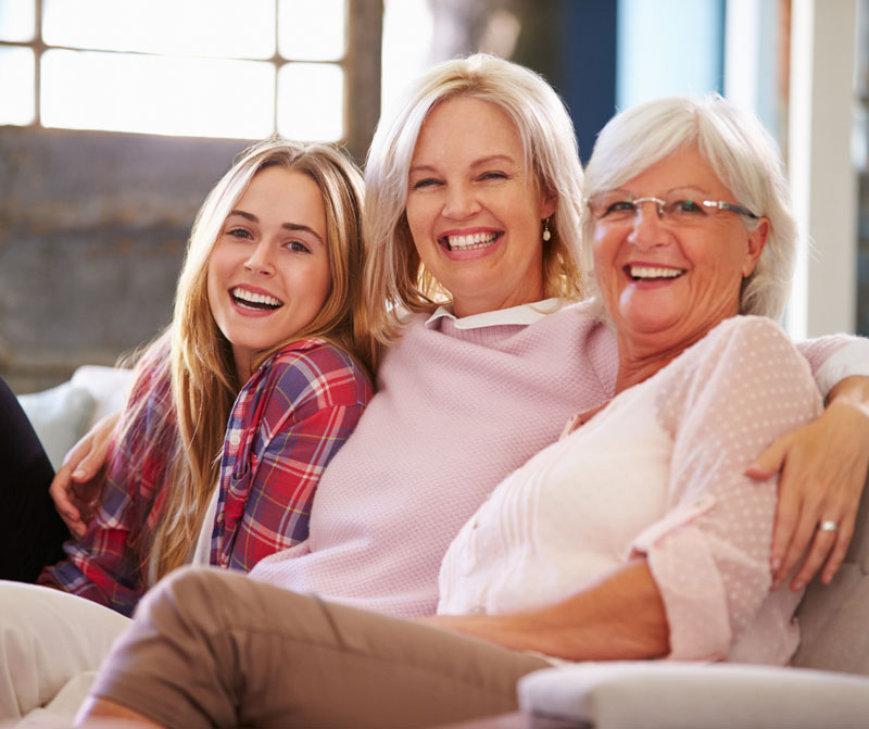 "Three generations of women smiling together, representing family history and breast cancer awareness"